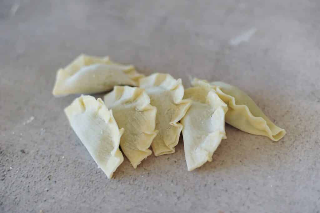 uncooked dumplings on grey bench