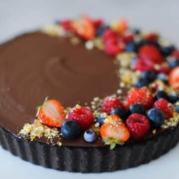 chocolate tart on a plate with berries and praline