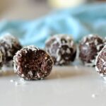 close up of chocolate bliss ball coated in coconut with bite missing