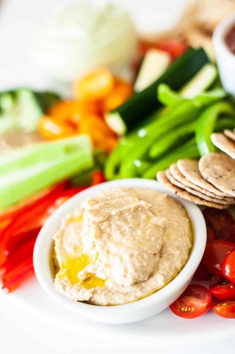 side view of hummus on a platter with chopped vegetables