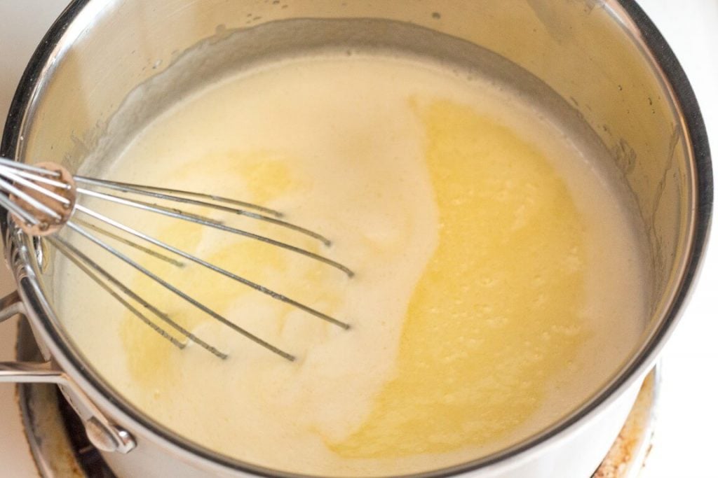 top view of sugar and water in saucepan with whisk