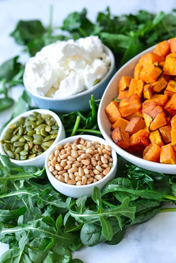white bowls containing pumpkin, pine nuts, cheese and seeds