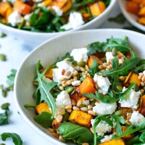 A white bowl containing salad and rocket