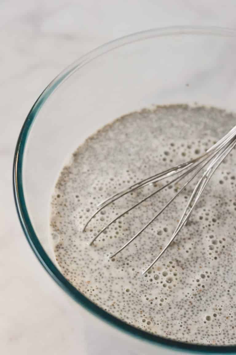 chia pudding and milk in glass bowl with whisk