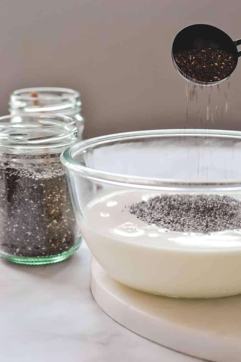 a bowl of milk with chia seeds being poured over the top