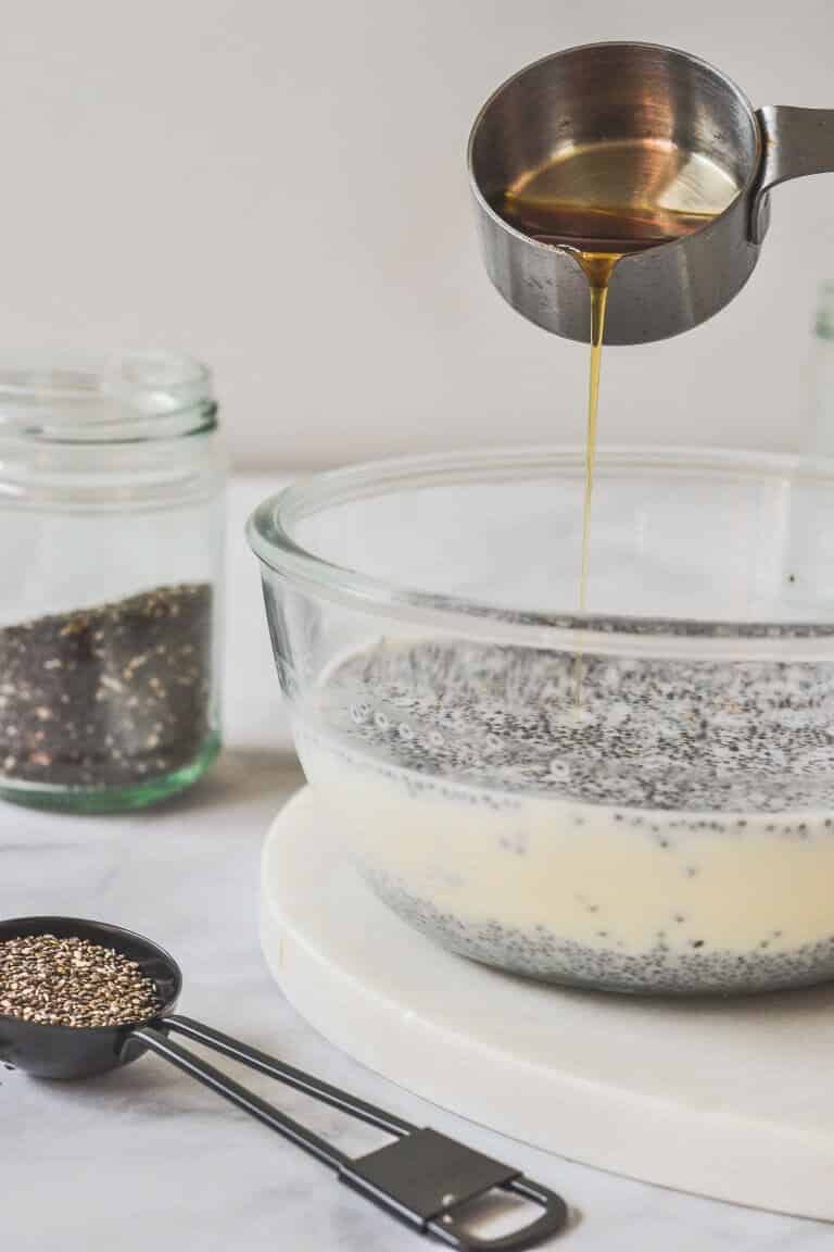 maple syrup poured over chia and milk in glass bowl