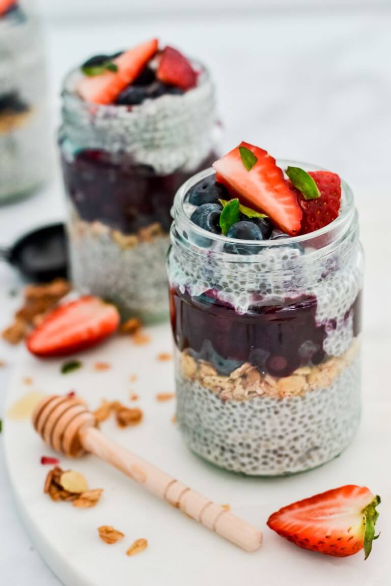 a close up of a glass jar containing chia, vanilla bean and berries