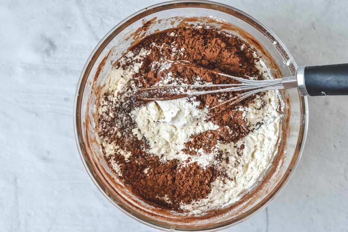 flour and cocoa in glass bowl with whisk