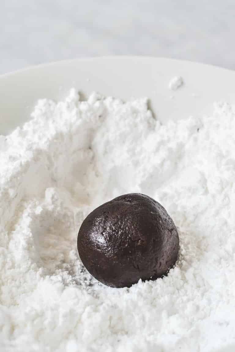 chocolate cookie dough ball in a pile of icing sugar