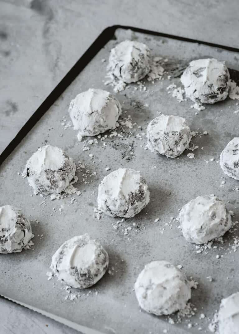 cookie dough balls covered in icing sugar on baking tray