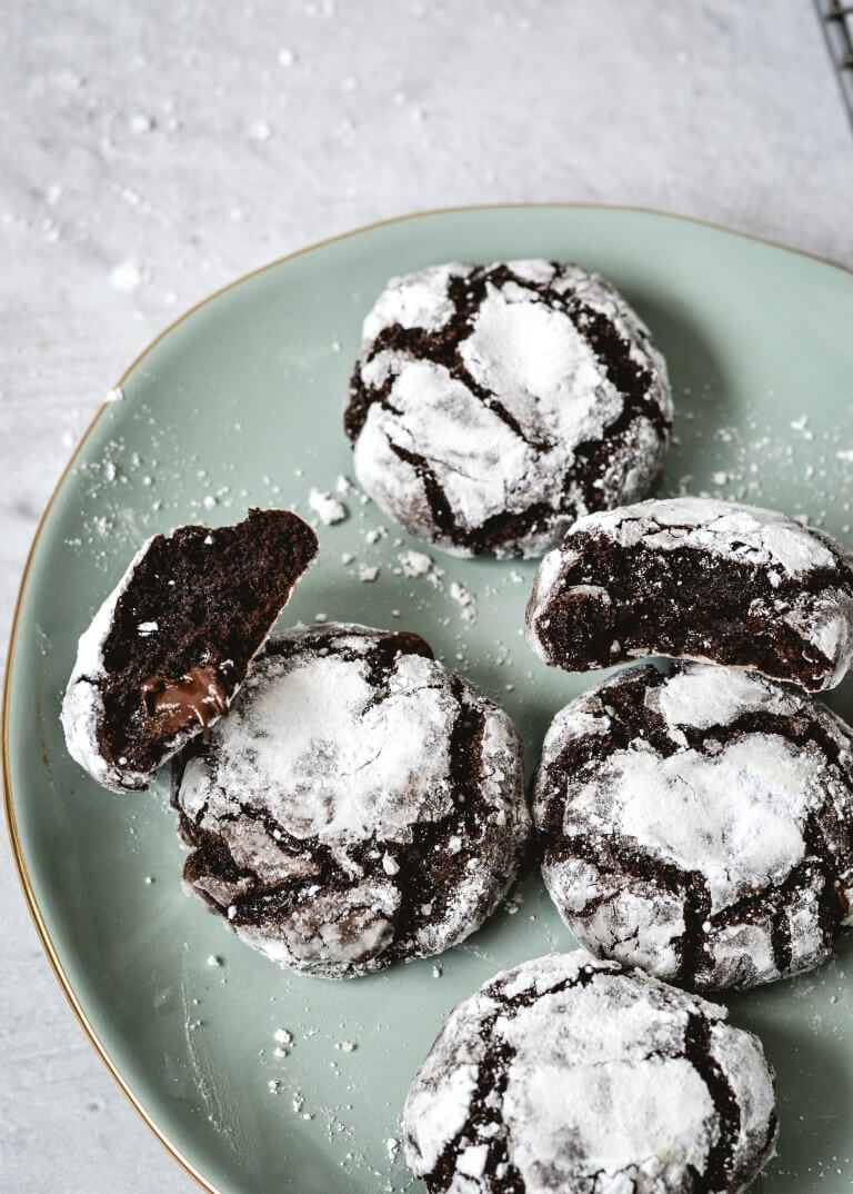 top view of chocolate cookies coated in confectioners sugar on green plate