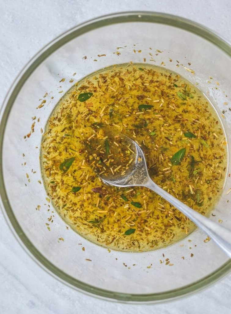 top view of a glass bowl containing marinade ingredients and a spoon