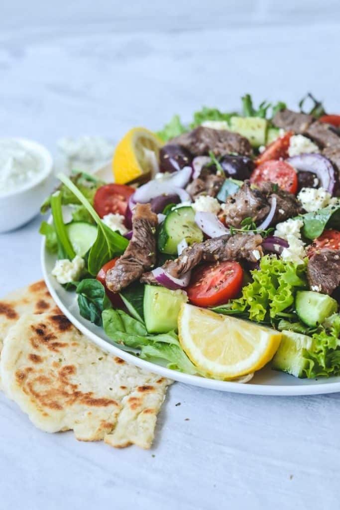 A plate of salad with flat bread on the side