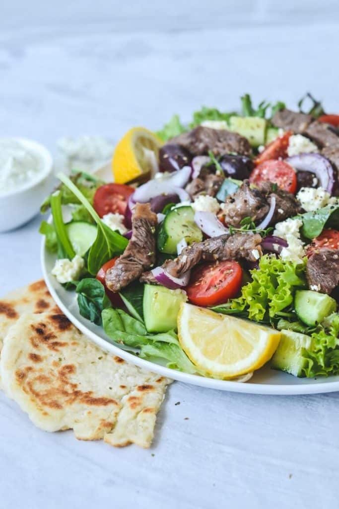 A plate of salad with flat bread on the side