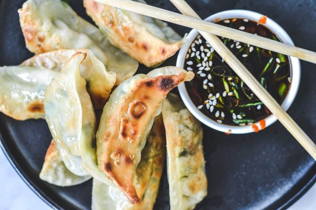 top view of dumplings with chopsticks and dipping sauce