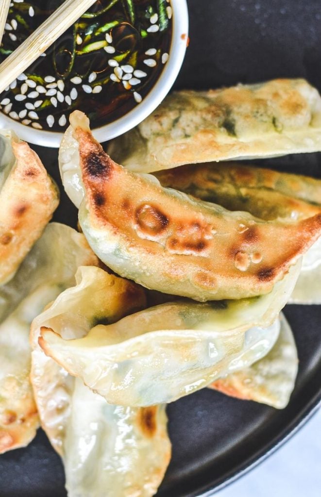 A close up of a plate of food, with gyoza with crispy edges