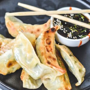 dumplings arranged on black plate with chopsticks