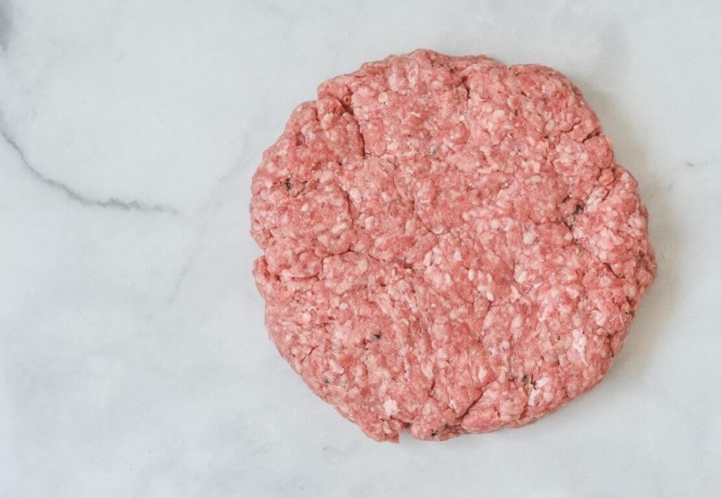 flattened beef patty on white board