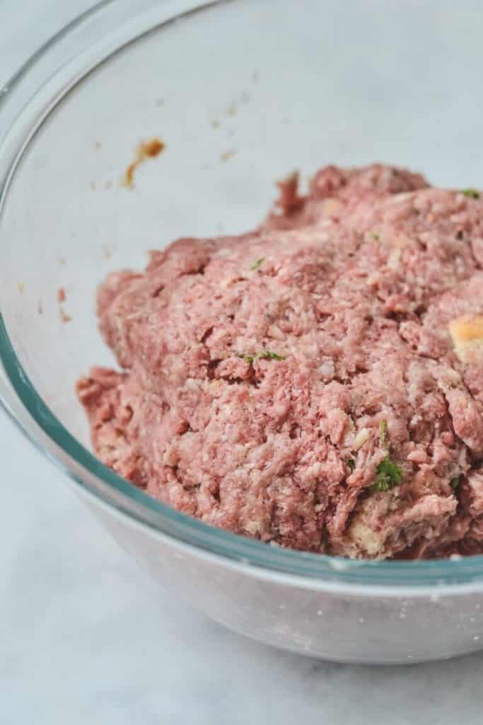 A close up of a bowl with meatball mixture