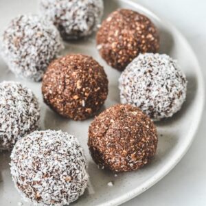 chocolate bliss balls in coconut on white plate