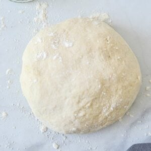 top view of pizza dough with sprinkled flour on white table