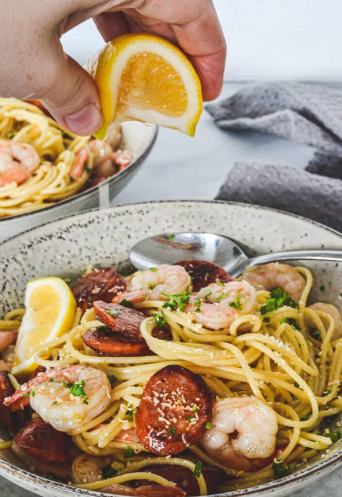 pasta-in-bowl-with-prawn-and-chorizo-hand-squeezing-lemon-juice