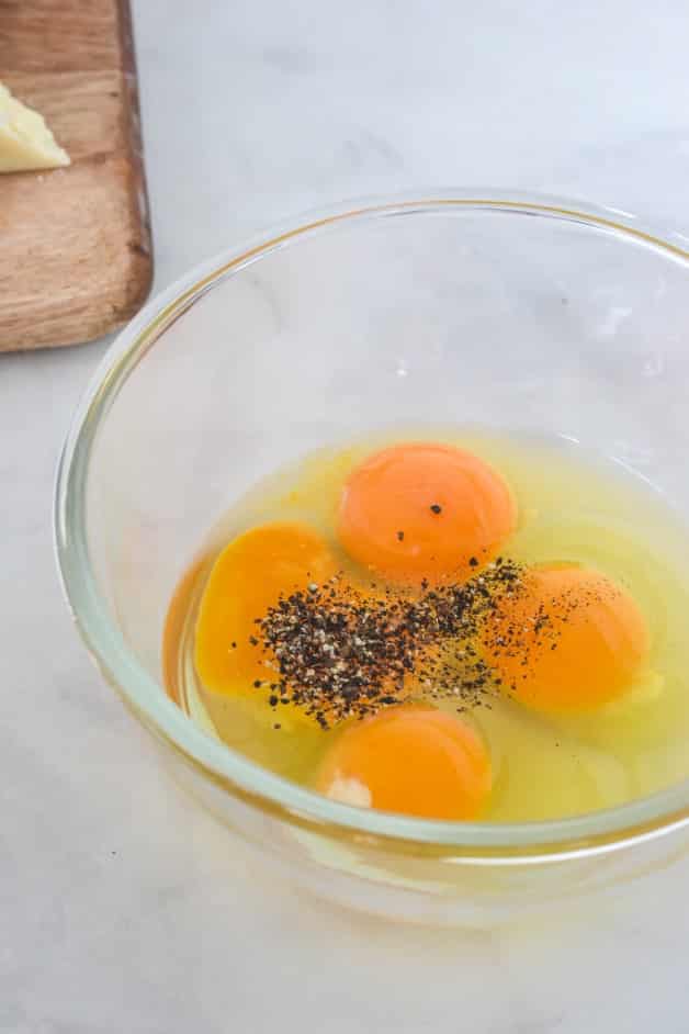 eggs and yolk in glass bowl with cracked pepper on top