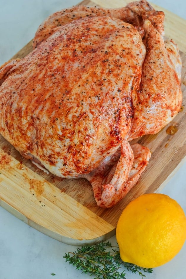 whole chicken covered in oil and spices on a wooden board