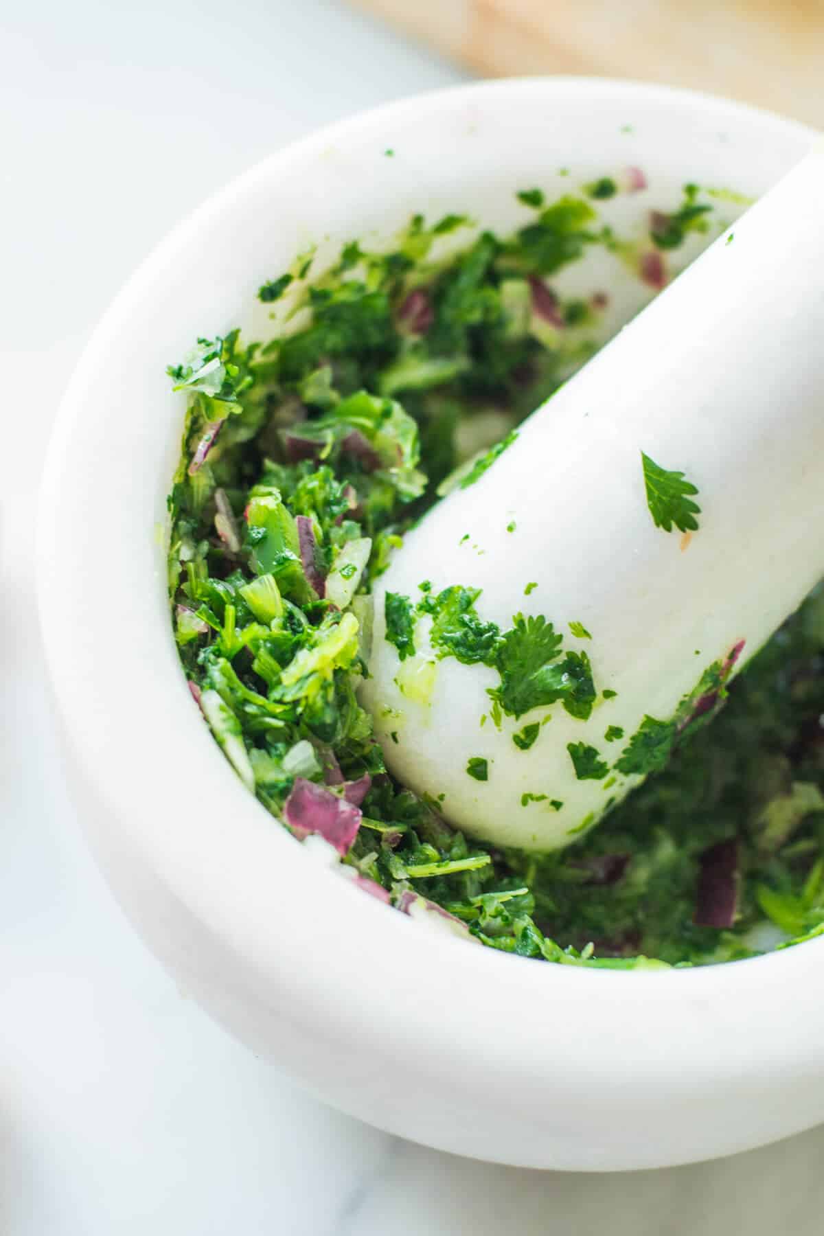 mashed onion and coriander in a white mortar and pestle