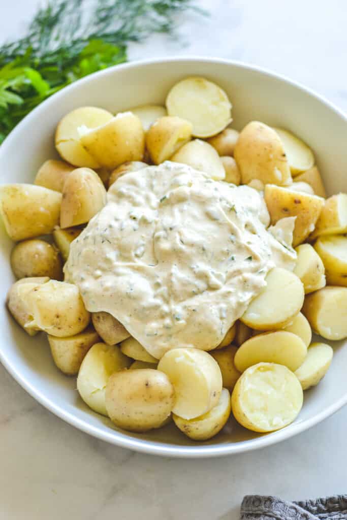cooked potatoes and dressing in white bowl