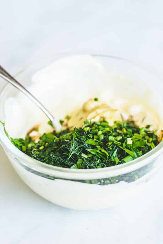 green herbs on top of mayonnaise in glass bowl