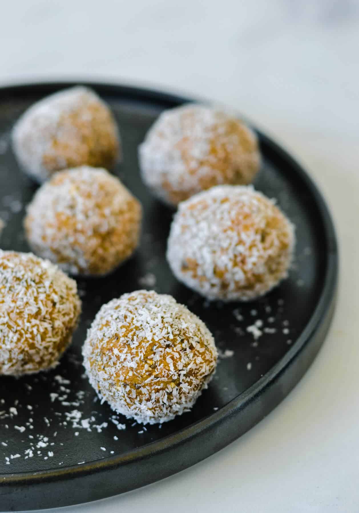 black plate with caramel bliss balls coated in coconut