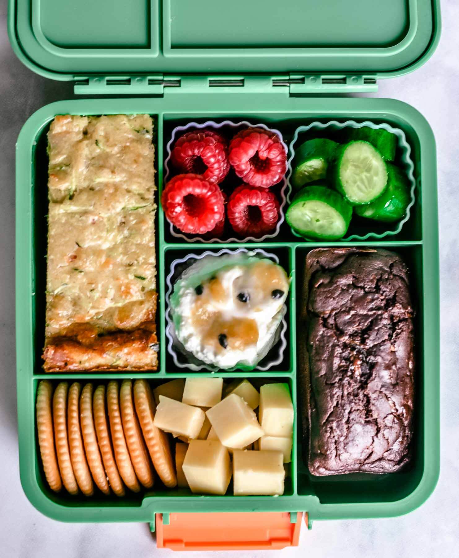 top view of a green bento lunchbox containing healthy foods