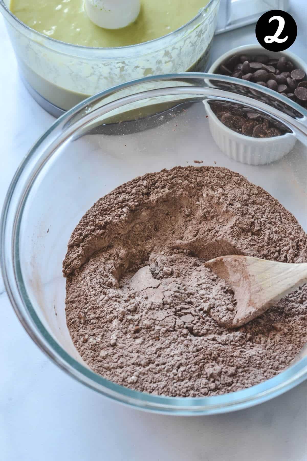 dry ingredients for chocolate muffins in a glass bowl with a wooden spoon