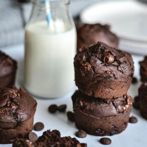 close up of chocolate muffins with a glass of milk and chocolate chips