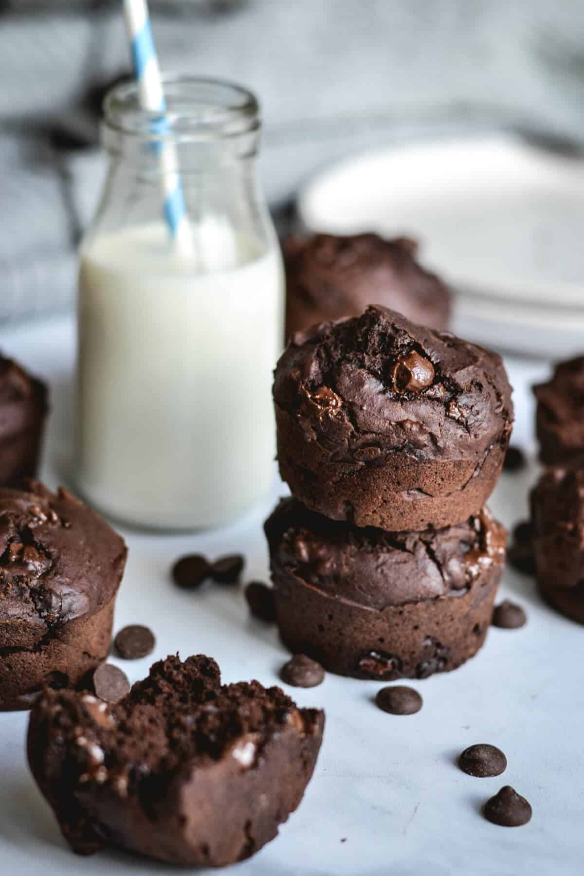 close up of chocolate muffins with a glass of milk and chocolate chips