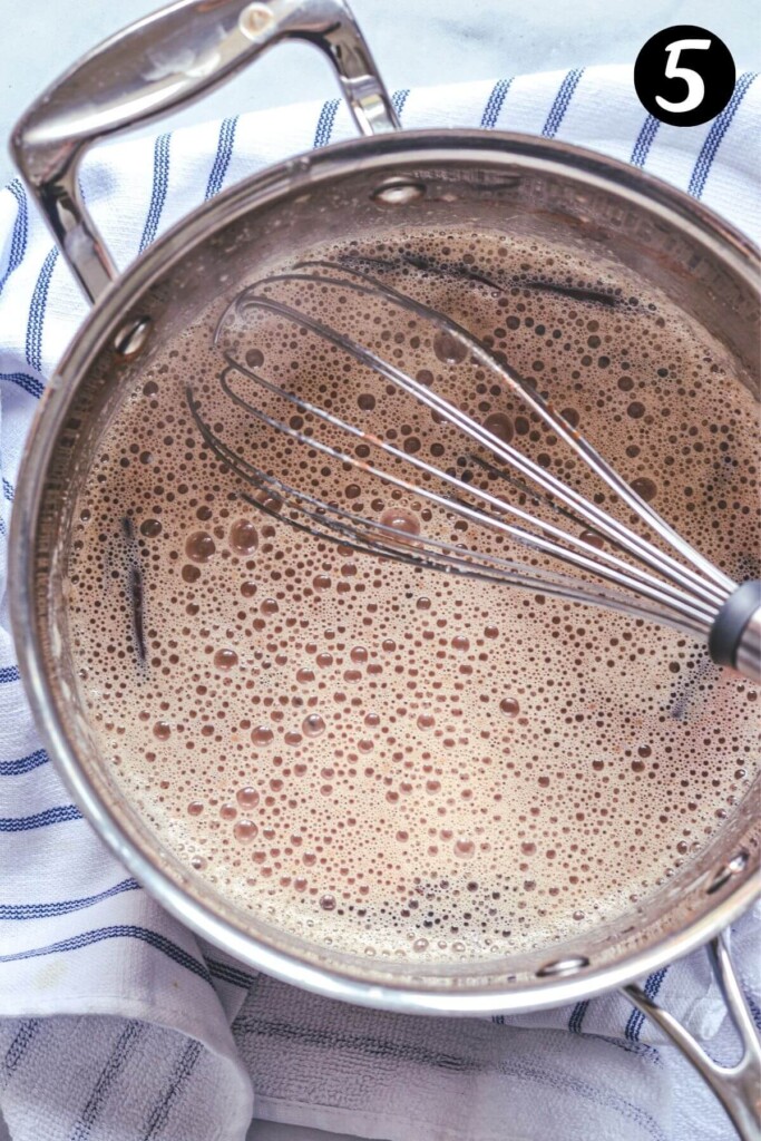 top view of a saucepan containing hot chocolate and a whisk