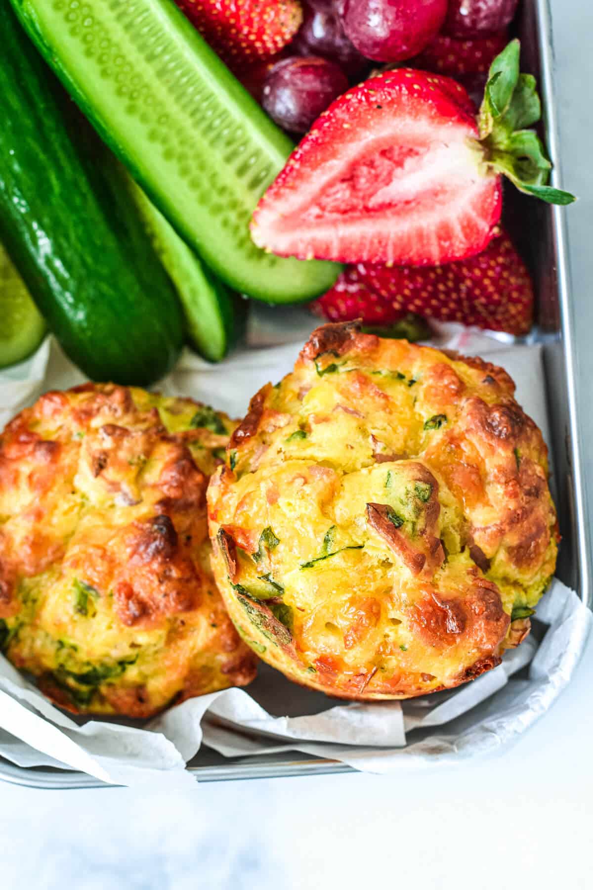 vegetable muffins in a lunchbox with fruit and cucumbers