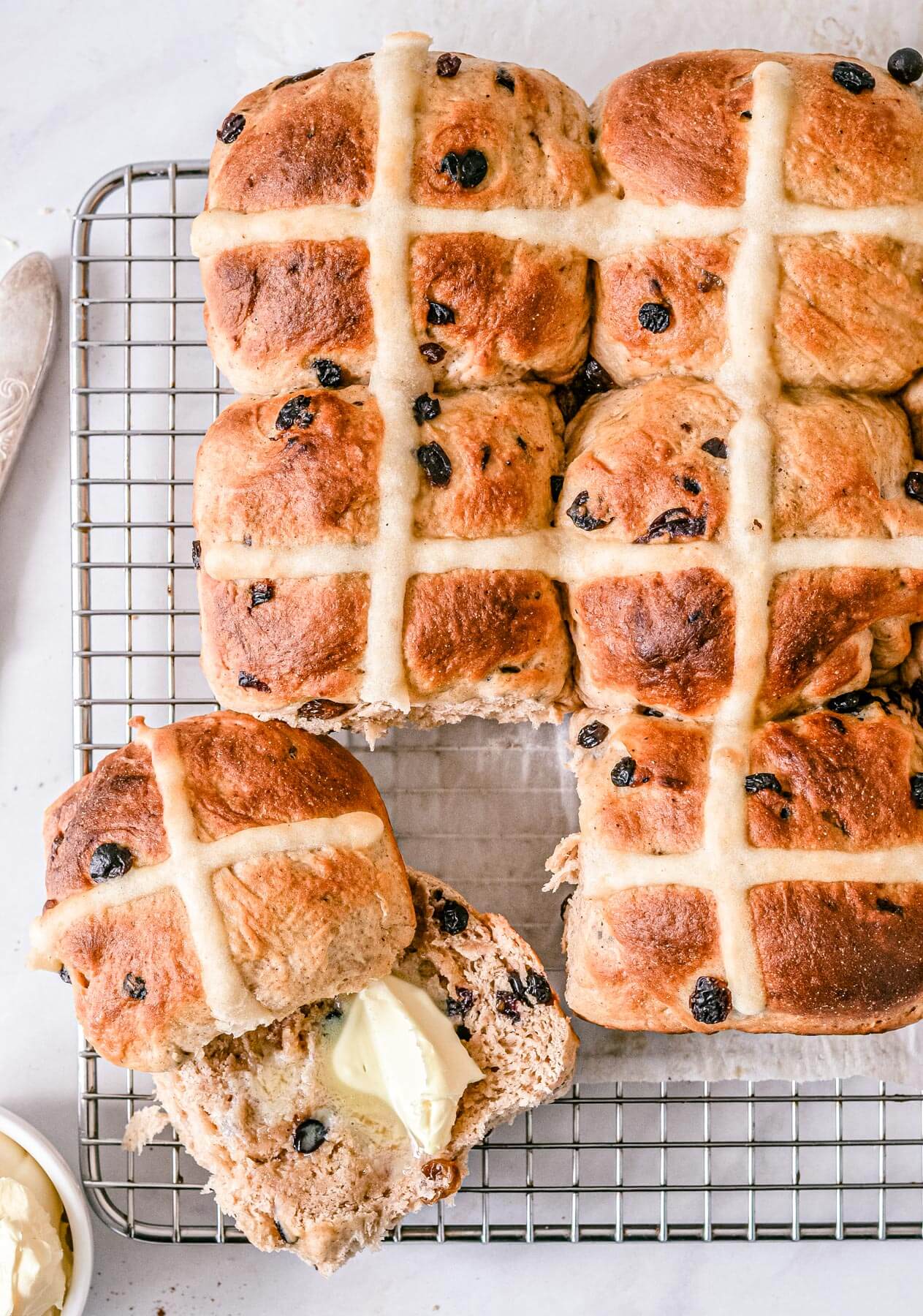 top view of finished hot cross funs with butter on a wire rack