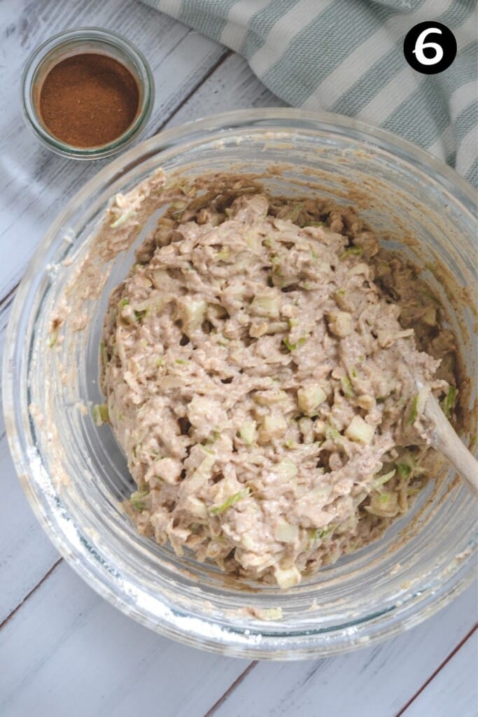 apple muffin batter in a glass bowl with a wooden spoon