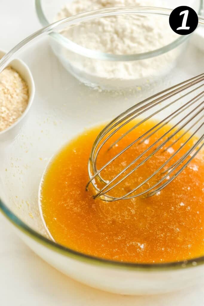 honey and wet ingredients in a glass bowl with a whisk.