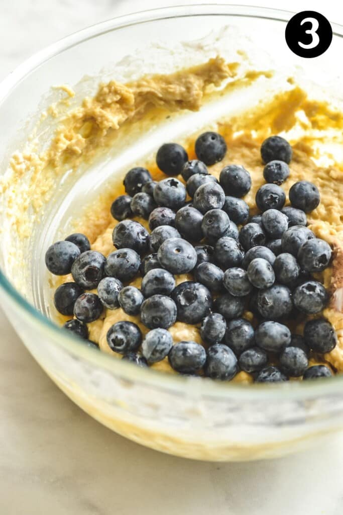 blueberries on cupcake batter in a glass bowl.