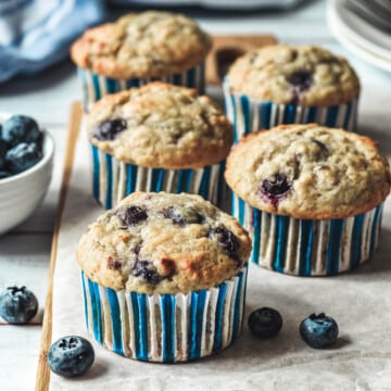 cupcakes arranged on a wooden board surrounded by blueberries.