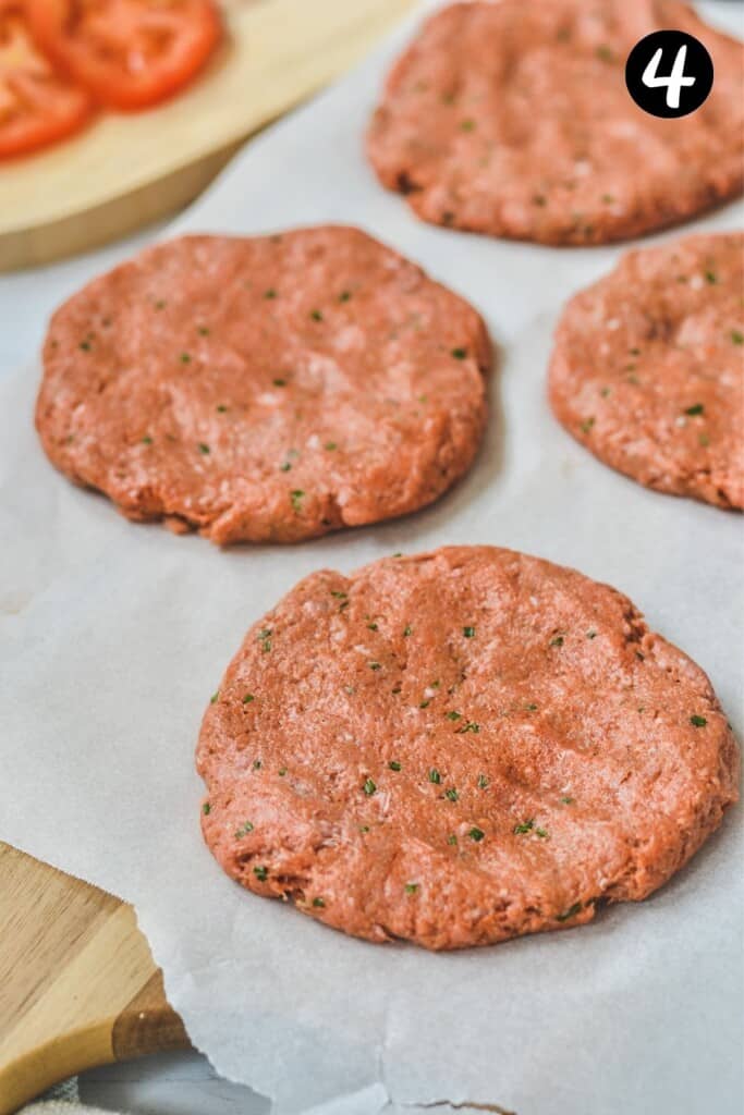 flattened burger patties on a piece of parchment paper