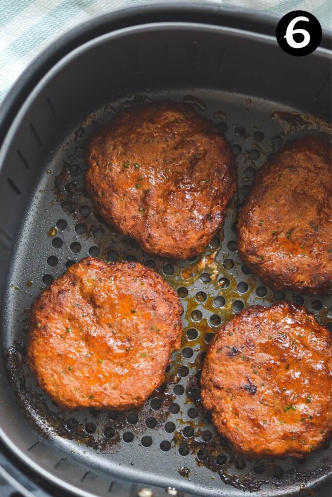 cooked turkey burger patties in an air fryer basket.