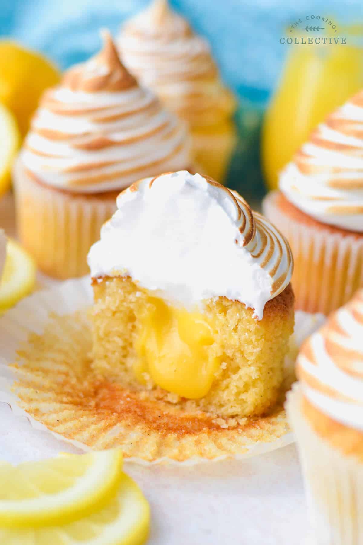 a lemon curd cupcake topped with meringue cut in half, showing the lemon curd filling.