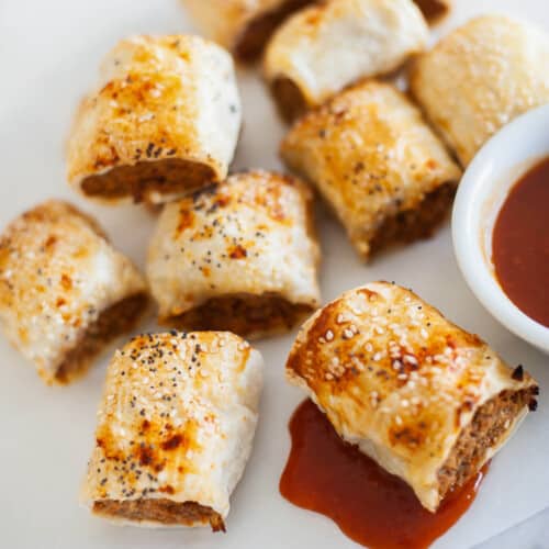 pork sausage rolls with tomato sauce on a white plate.