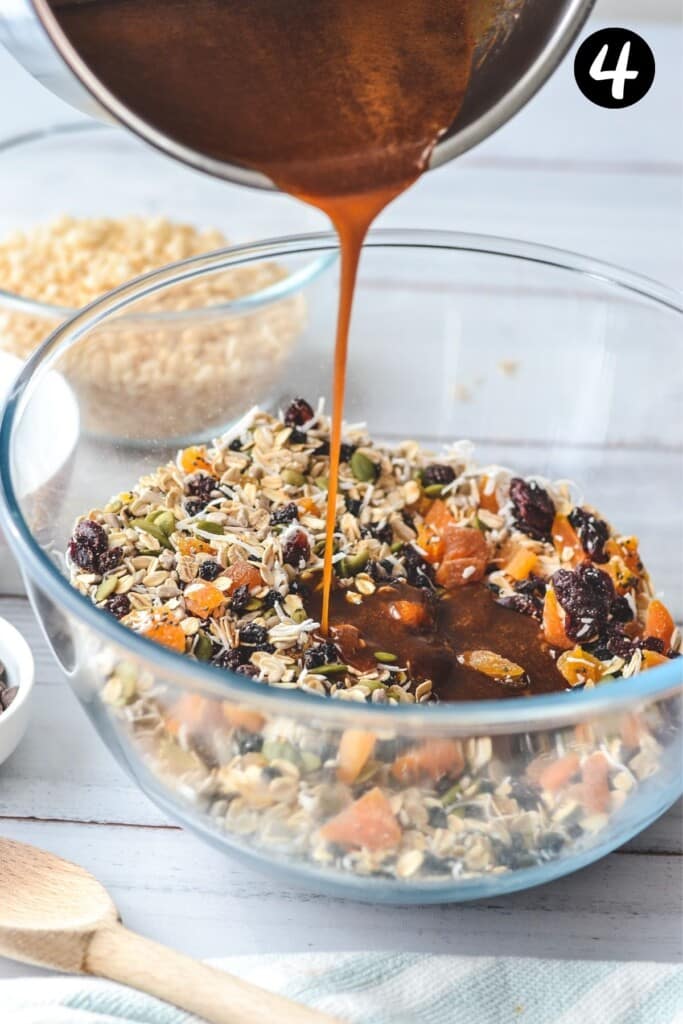 honey mixture being poured over dry muesli ingredients