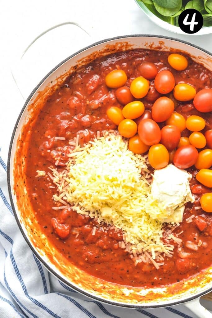 tomato sauce with cream cheese and whole cherry tomatoes in a pan
