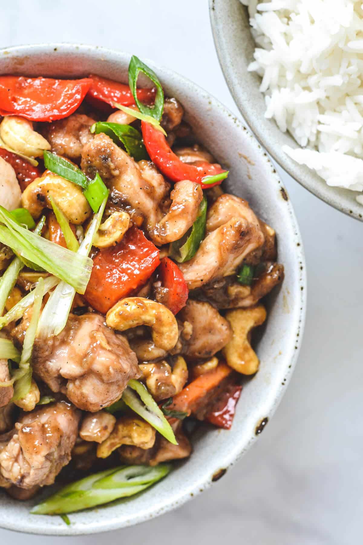 top view of chicken stir fry with cashews and a bowl of rice